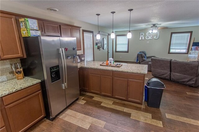 kitchen with ceiling fan, hanging light fixtures, stainless steel fridge with ice dispenser, and light stone counters