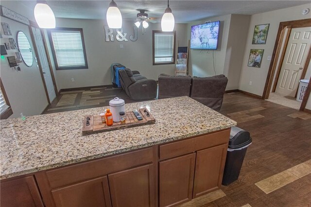 kitchen with light stone countertops, dark hardwood / wood-style flooring, ceiling fan, and decorative light fixtures