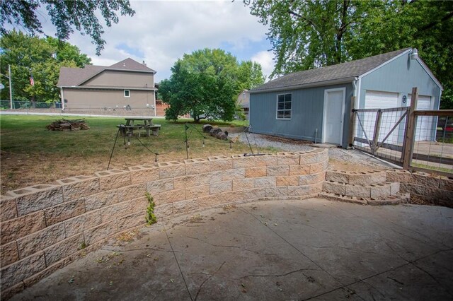 view of patio / terrace featuring an outbuilding, a garage, and a fire pit