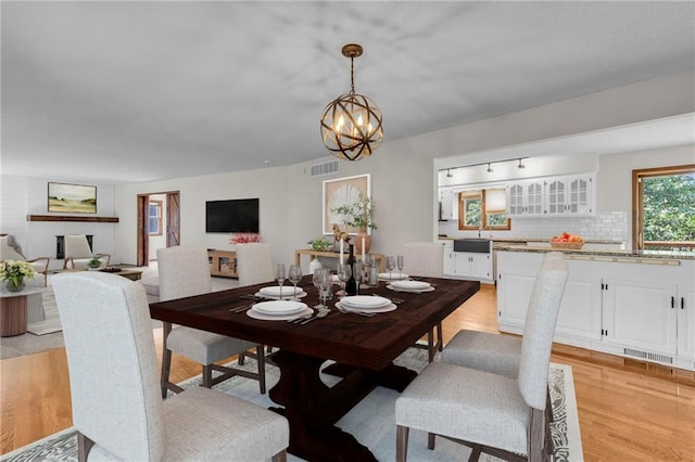 dining room featuring sink, light wood-type flooring, and a chandelier