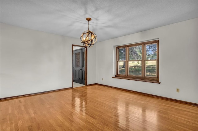 unfurnished room with a textured ceiling, light hardwood / wood-style flooring, and a chandelier