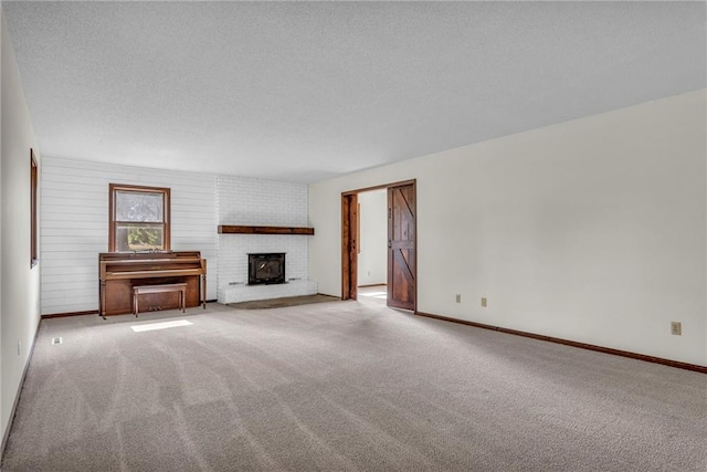 unfurnished living room with light colored carpet, a textured ceiling, and a brick fireplace