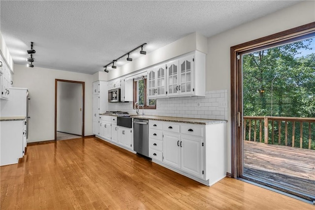 kitchen with a textured ceiling, appliances with stainless steel finishes, tasteful backsplash, light wood-type flooring, and white cabinets