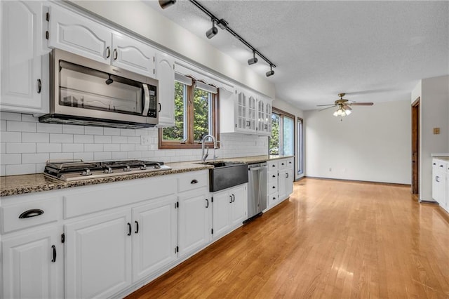 kitchen with stainless steel appliances, light hardwood / wood-style floors, white cabinetry, ceiling fan, and a textured ceiling