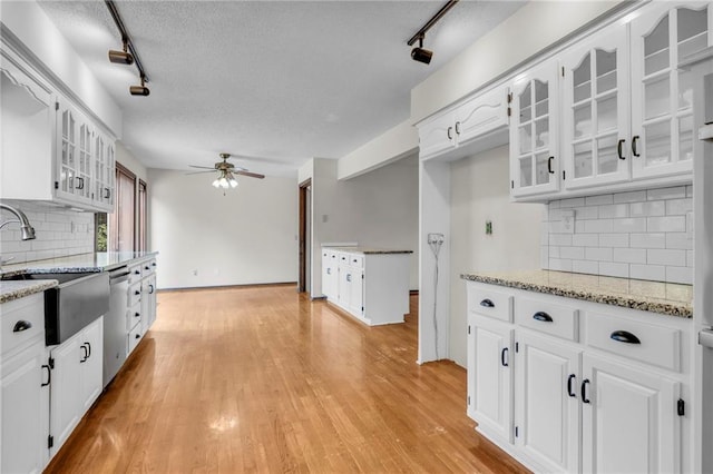 kitchen with light wood-type flooring, white cabinets, and track lighting