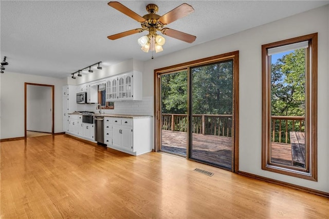 kitchen with white cabinets, light wood-type flooring, stainless steel appliances, and ceiling fan