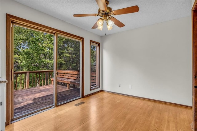 spare room with a textured ceiling, a wealth of natural light, light hardwood / wood-style flooring, and ceiling fan