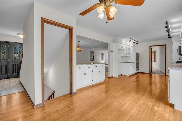 interior space featuring appliances with stainless steel finishes, ceiling fan, white cabinetry, and light hardwood / wood-style flooring