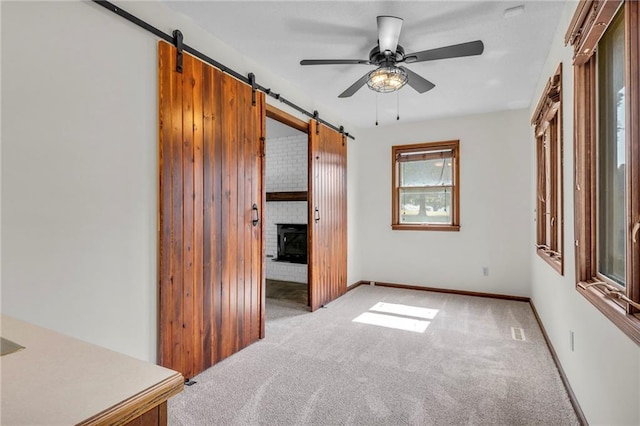 carpeted bedroom featuring a barn door and ceiling fan