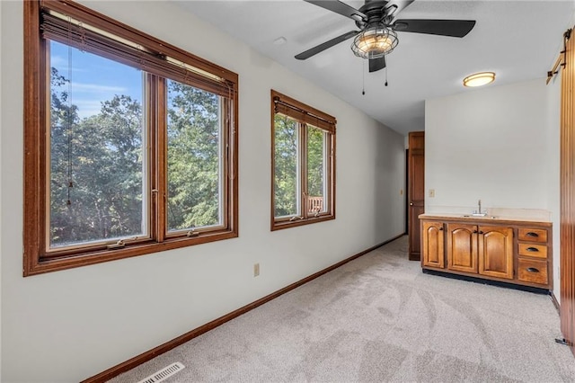 empty room with ceiling fan and light colored carpet