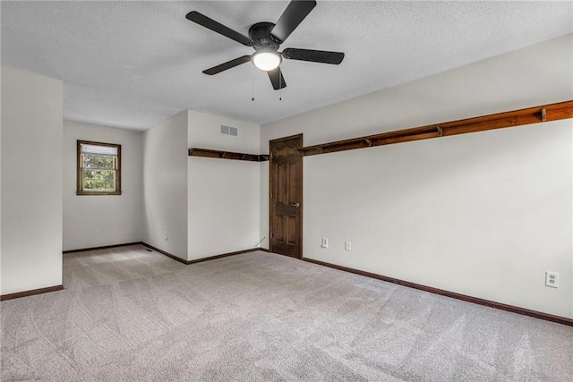 carpeted spare room with a textured ceiling and ceiling fan