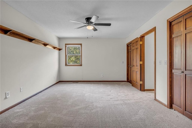 unfurnished bedroom featuring light carpet, a textured ceiling, and ceiling fan