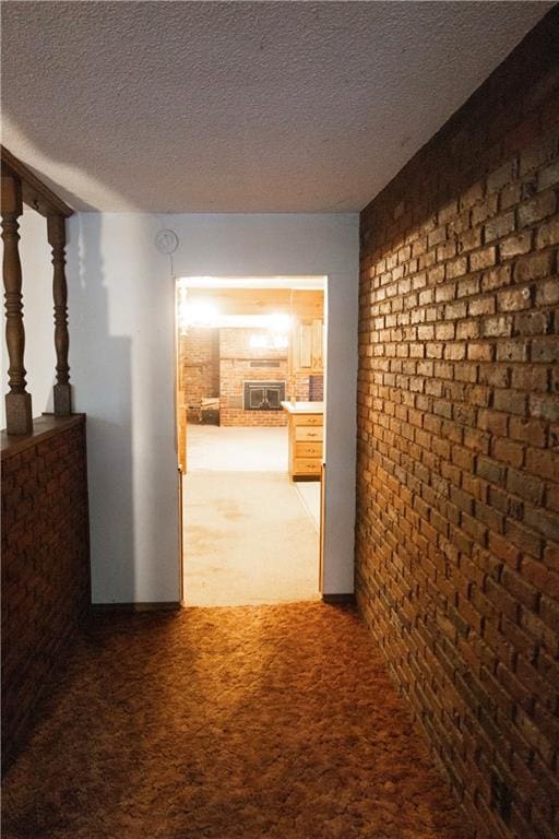 hallway featuring a textured ceiling, brick wall, and carpet