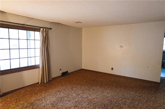 carpeted empty room with a textured ceiling