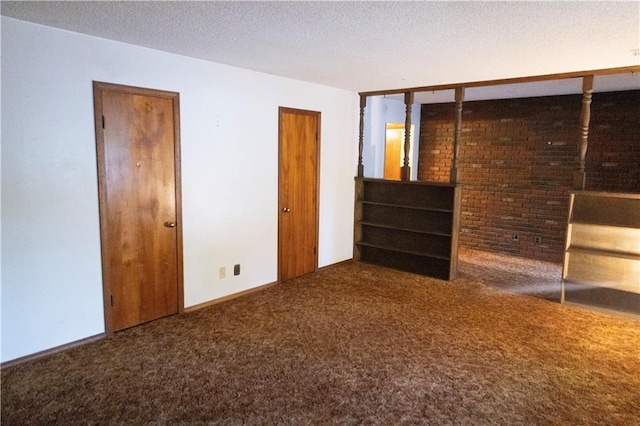 unfurnished bedroom with a textured ceiling, brick wall, and carpet floors