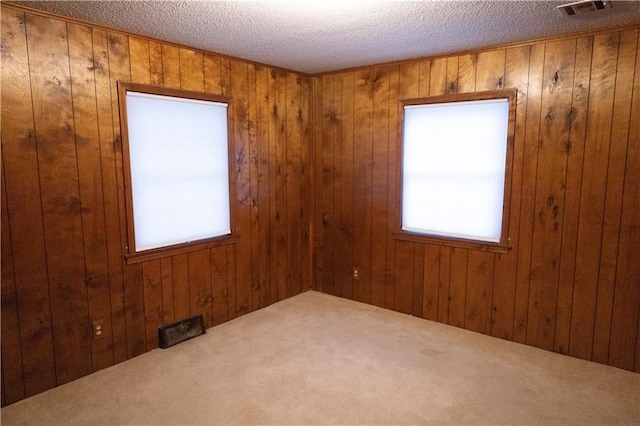 carpeted empty room featuring a textured ceiling and wooden walls