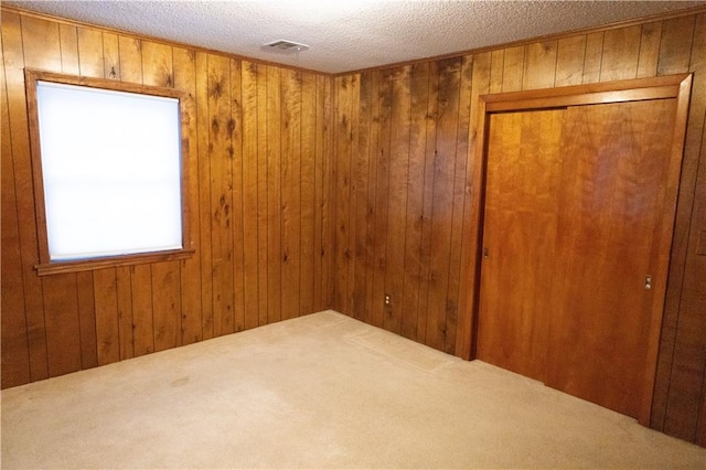 empty room featuring wood walls, carpet flooring, and a textured ceiling