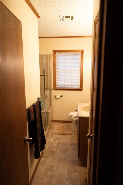 bathroom with a textured ceiling, crown molding, toilet, a shower with shower door, and vanity