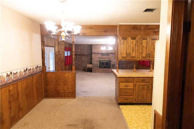 kitchen with wood walls, an inviting chandelier, a fireplace, light carpet, and kitchen peninsula