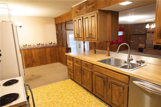 kitchen featuring white appliances, light carpet, sink, wood walls, and a textured ceiling