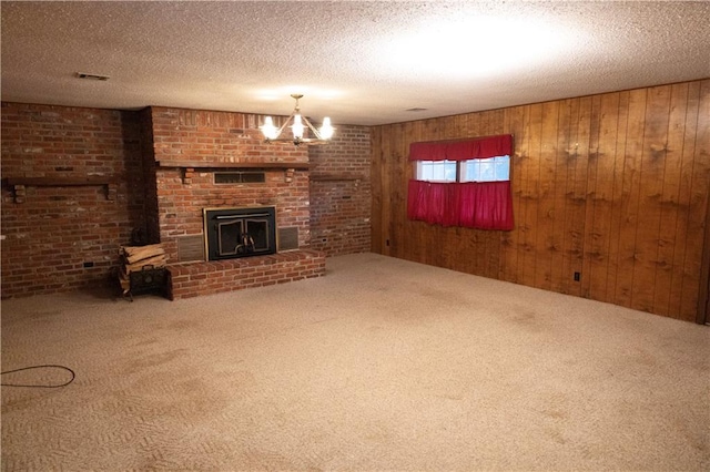 unfurnished living room featuring a fireplace, a textured ceiling, wooden walls, and carpet flooring