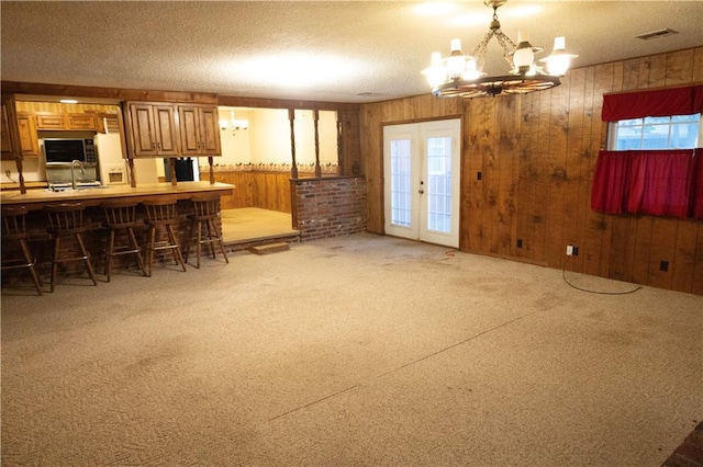 unfurnished living room with a textured ceiling, wood walls, and a chandelier