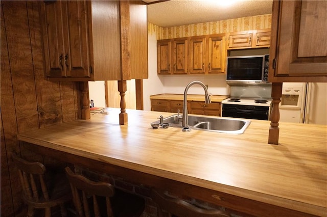 kitchen with wooden counters, white appliances, and sink