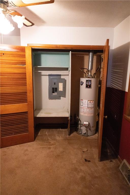 utility room featuring electric panel and gas water heater