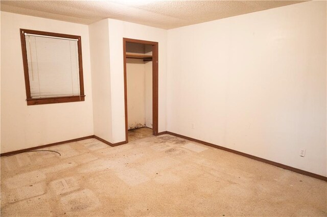 unfurnished bedroom featuring a closet, light carpet, and a textured ceiling