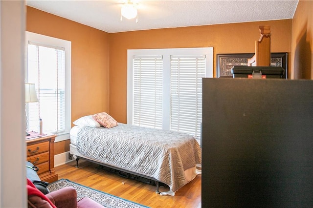 bedroom with multiple windows, ceiling fan, hardwood / wood-style floors, and a textured ceiling