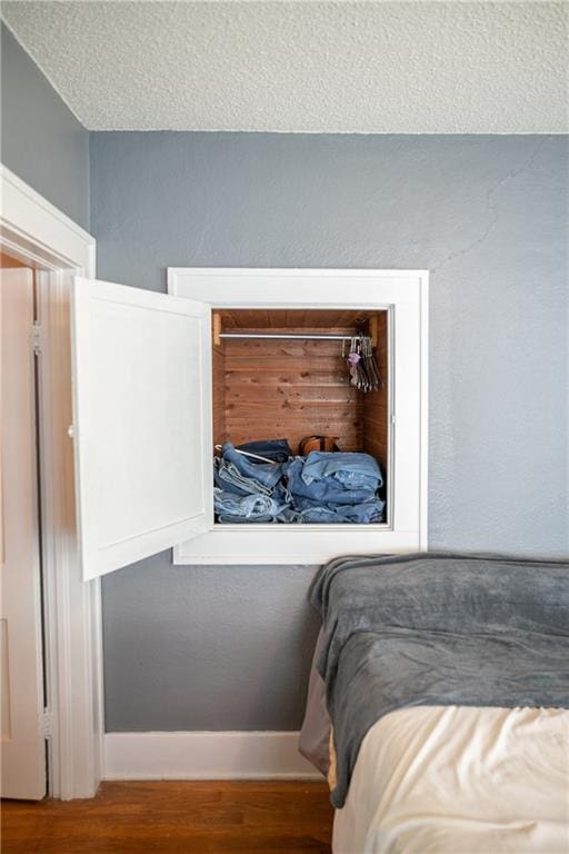 bedroom with a textured ceiling and wood-type flooring