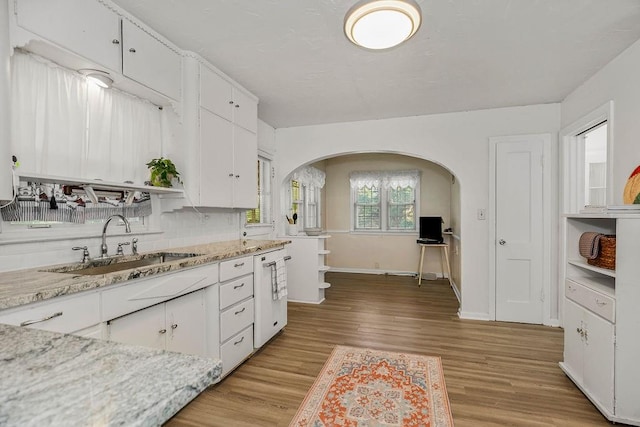 kitchen featuring light stone counters, sink, tasteful backsplash, white cabinetry, and light wood-type flooring