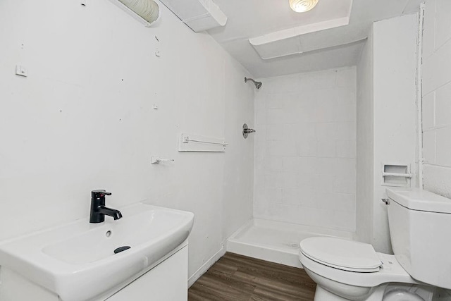 bathroom featuring a tile shower, vanity, toilet, and hardwood / wood-style flooring