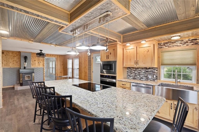 kitchen featuring a wood stove, a center island, stainless steel appliances, decorative light fixtures, and dark wood-type flooring