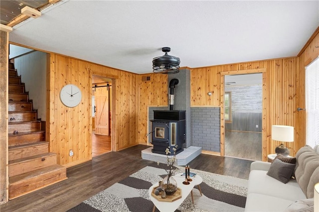 living room with crown molding, wood walls, a wood stove, and dark hardwood / wood-style flooring