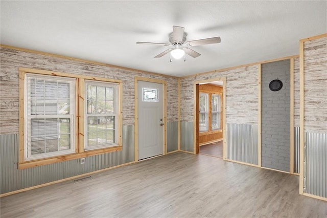 unfurnished room with wood walls, wood-type flooring, and ceiling fan