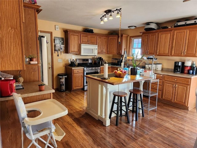 kitchen featuring stainless steel range with gas stovetop, dark hardwood / wood-style flooring, a breakfast bar area, and a center island