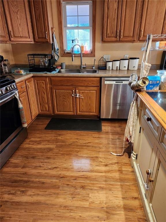 kitchen with stainless steel appliances, sink, and light hardwood / wood-style floors