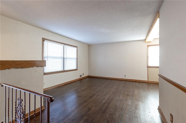 spare room featuring a textured ceiling and dark hardwood / wood-style flooring