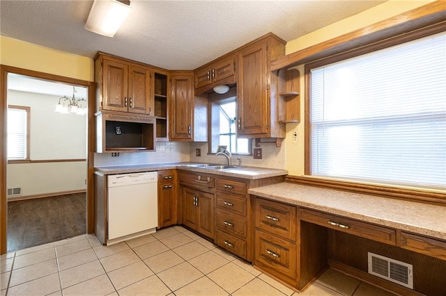 kitchen featuring dishwasher, sink, light tile patterned floors, and hanging light fixtures