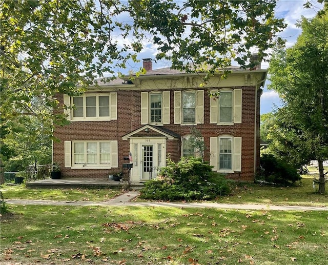 view of front facade featuring a front yard, brick siding, and a chimney