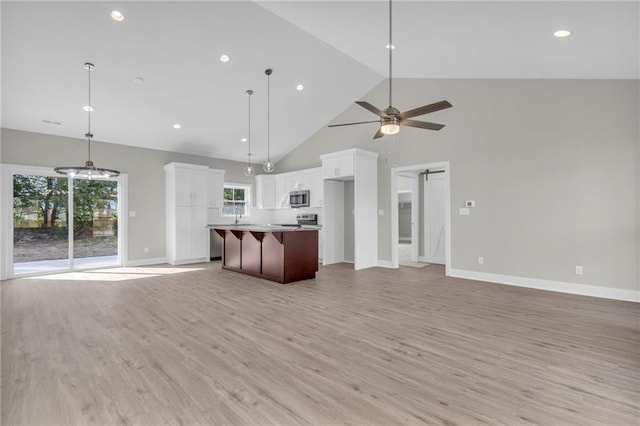 kitchen featuring hanging light fixtures, white cabinets, stainless steel appliances, a center island, and ceiling fan