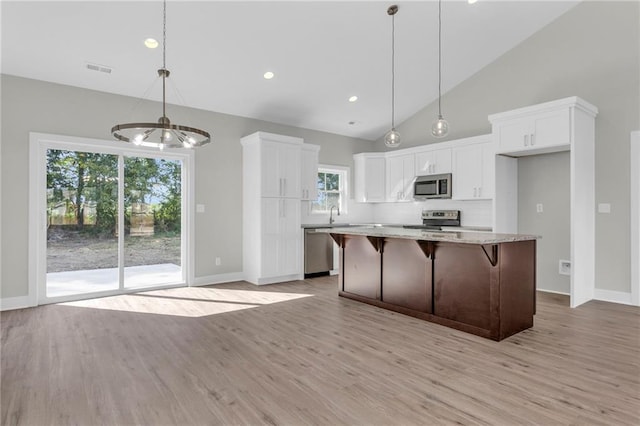 kitchen featuring stainless steel appliances, white cabinets, a center island, and plenty of natural light