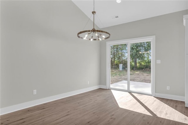 spare room featuring wood-type flooring, vaulted ceiling, and a chandelier