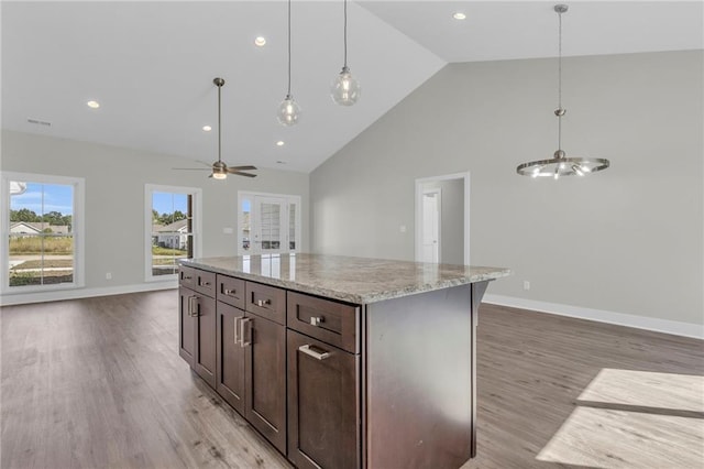 kitchen featuring light hardwood / wood-style floors, high vaulted ceiling, ceiling fan with notable chandelier, pendant lighting, and a center island