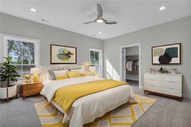 carpeted bedroom featuring ceiling fan, a closet, multiple windows, and a spacious closet