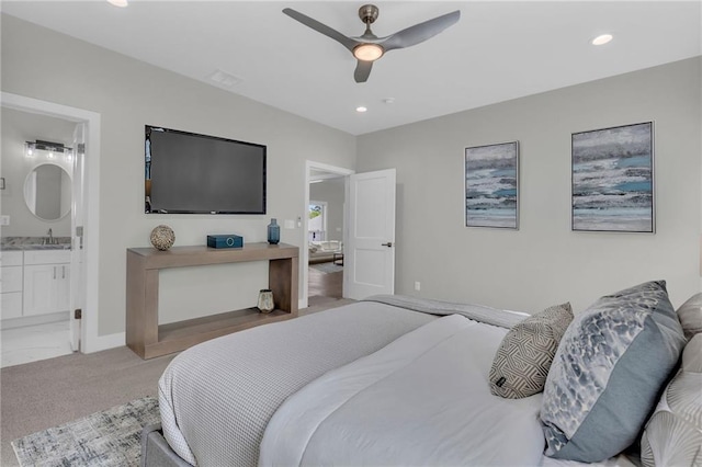 bedroom with ceiling fan, sink, connected bathroom, and light carpet