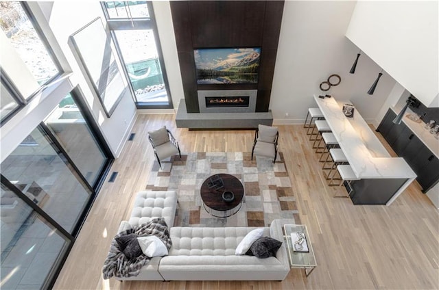 living room with a high ceiling, a wealth of natural light, and light hardwood / wood-style floors