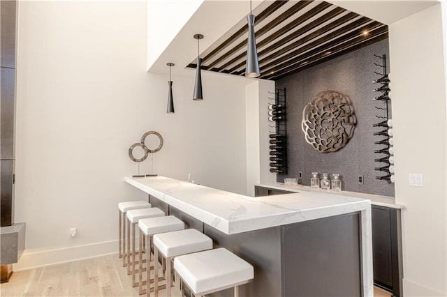 bar featuring light wood-type flooring and light stone countertops