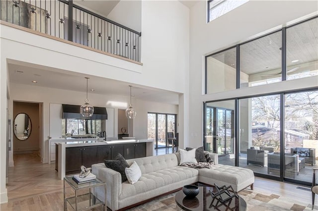 living room featuring light parquet flooring, a healthy amount of sunlight, a chandelier, and a high ceiling